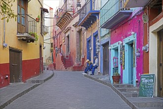 Colourful colonial era houses with balconies in alley paved with square cut stones in the city