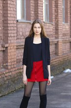 Street fashion, urban style. Girl in jacket, shirt, skirt and high boots