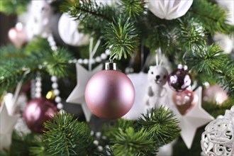 Close up of decorated Christmas tree with pink and white tree ornaments like baubles, stars and