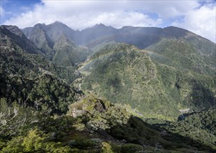 Densely overgrown steep mountains with rainbow, green mountain landscape, view from Miradouro dos