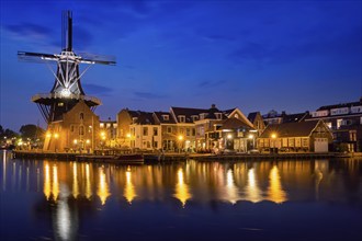 View of Harlem cityscape with landmark windmill De Adriaan on Spaarne river in the night