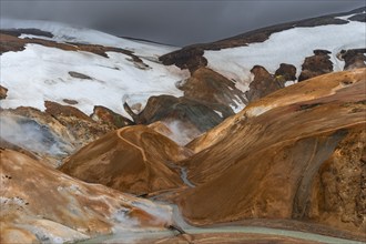 Bridge and steaming streams between colourful rhyolite mountains with snowfields, Hveradalir