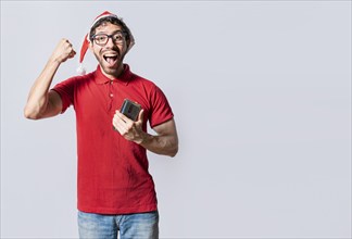 Happy guy in christmas hat holding cellphone celebrating. People with santa hat celebrating a