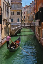 VENICE, ITALY, JULY 19, 2018: Narrow canal between colorful old houses with gondola boat with