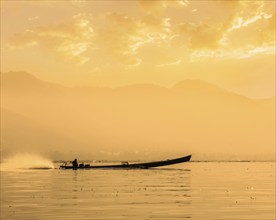 Speeding motor boat silhouette on Inle lake on sunset, Myanmar, Asia