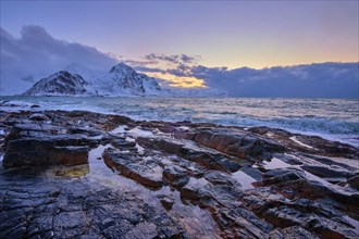 Beach of Norwegian sea on rocky coast in fjord on sunset in winter. Vareid beach, Lofoten islands,