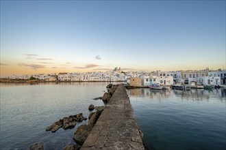 Harbour wall, view of the town of Naoussa and blue sea, at sunset, harbour with fishing boats and