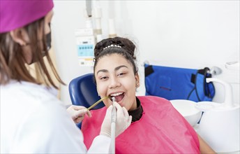 Stomatologist woman with drill cleaning patient girl mouth. Stomatologist drilling and cleaning a