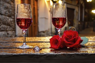 Red roses, golden rings and glasses of wine on an old wooden table, AI generated