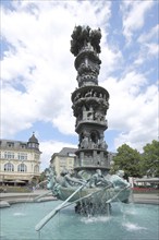 Fountain with sculptures and figures, rowing boat with oarsman and history column, obelisk,