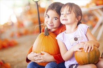 Adorable little girls holding pumpkins at A pumpkin patch