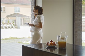 Attractive pregnant woman calls a doctor for an online consultation or to find out the results of