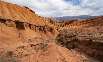 Eroded mountain landscape with sandstone cliffs, canyon with red and orange rock formations,