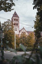 View of a church with red tiled roof and bell tower surrounded by autumnal trees, Stuttgart,