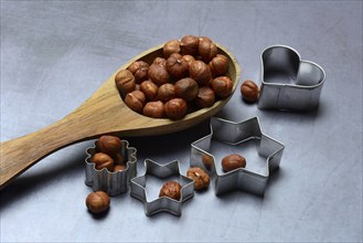 Wooden ladle with hazelnuts, cookie cutters, baking ingredient