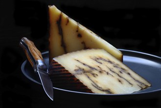 Sheep cheese with black garlic on plate with knife, Spain, Europe