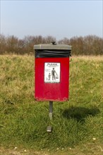 Red dog waste bin, Cudmore Grove Country Park, East Mersea, Mersea Island, Essex, England, UK