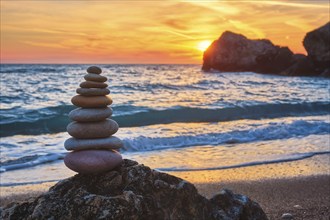 Cairn stack of stones pebbles cairn on the beach coast of the seaon sunset. Agios Ioannis beach,