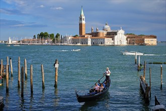 VENICE, ITALY, JUNE 27, 2018: Gondolier with tourists in gondola in lagoon of Venice by Saint Mark