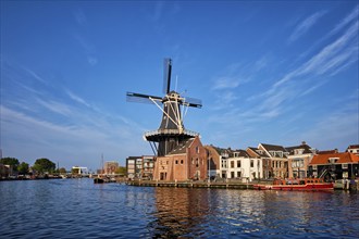 Harlem cityscape, landmark windmill De Adriaan on Spaarne river with boats. Harlem, Netherlands