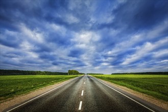 Travel concept background, road under dramatic stormy cloudy sky