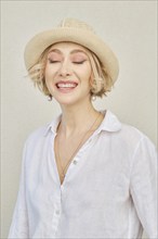 Lifestyle portrait of beautiful young woman with healthy skin in white shirt and straw hat