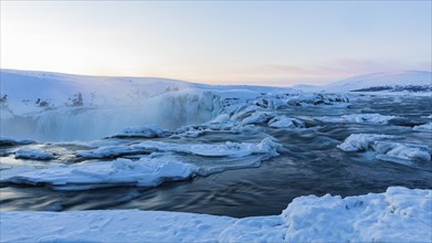 Icefall at the edge of the Godafoss waterfall at dawn, snow-covered landscape, Northern Iceland