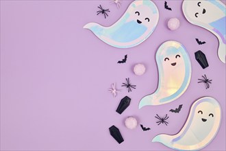 Cute pastel colored Halloween party flat lay with ghost shaped plates, spiders, pumpkins and