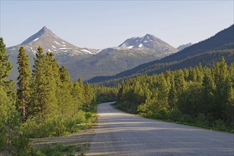 Narrow, traffic-free road leads through rugged mountain landscape, wilderness, Stewart Cassiar