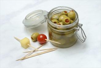 Green olives in glass and on toothpicks with tomato and cheese cubes