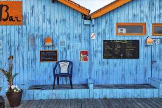 Colourful hut, wooden facade of a bar with orange sign and menu, advertising alcoholic beverages,