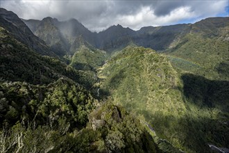 Densely overgrown steep mountains with rainbow, green mountain landscape, view from Miradouro dos