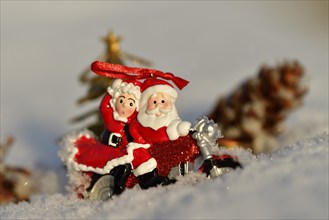 Christmas decorations, Santa and Mrs Claus riding through the snow on a motorbike