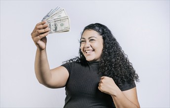 Excited latin girl holding dollar cash isolated. Victorious young woman holding money celebrating