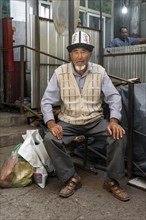 Man with traditional clothes shopping, market stall, Uzgen Bazaar, Ösgön, Osh region, Kyrgyzstan,