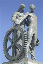 War memorial with two figures and cogwheel, sculptures, Rüsselsheim, Hesse, Germany, Europe