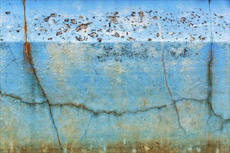 Dirty broken wall in a swimming pool, cracks, peeling blue colour, dilapidated swimming pool, lost