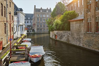 Famous place of Bruges, Rozenhoedkaai old houses along canal with tree and boats. Brugge, Belgium,