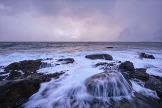 Beach of Norwegian sea on rocky coast in fjord on sunset in winter. Vareid beach, Lofoten islands,