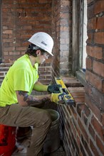 Detroit, Michigan, Journeyman bricklayer Tyler Tamer replaces bricks inside a bell tower of the