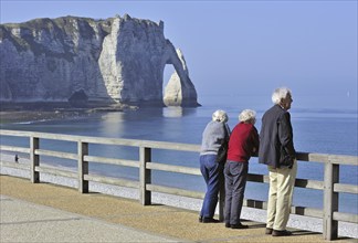 Elderly tourists and the Porte D'Aval, a natural arch in the chalk cliffs at Etretat, Côte