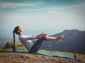 Yoga outdoors, young sporty fit woman doing Ashtanga Vinyasa Yoga asana Navasana, boat pose, in