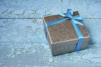 Gift birthday Christmas present concept, silver gift box with blue ribbon on blue painted wooden