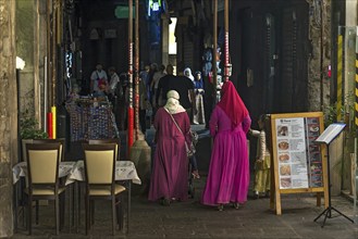 Women with colourful robes in the historic arcades at the harbour, Genoa, Italy, Europe