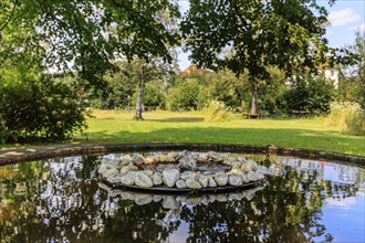 Small fountain and water bowl with stones under trees, Schlehdorf Monastery, Bavaria, Germany,