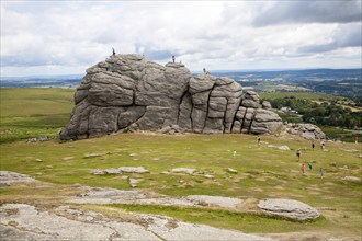 People scrambling on the granite tor of Haytor, Dartmoor national park, Devon, England, UK