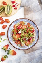 Vegetarian fruits and vegetables salad of strawberry, kiwi, tomatoes, microgreen sprouts on white