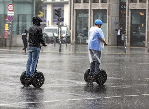 Tourists riding Segway personal transporters across a street in heavy rain, Berlin, 23 06 2023