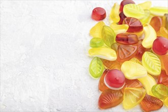 Various fruit jelly candies on gray concrete background. side view, copy space