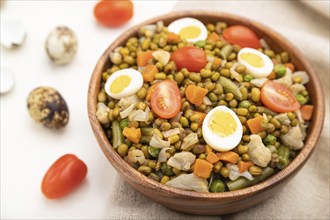 Mung bean porridge with quail eggs, tomatoes and microgreen sprouts on a white wooden background